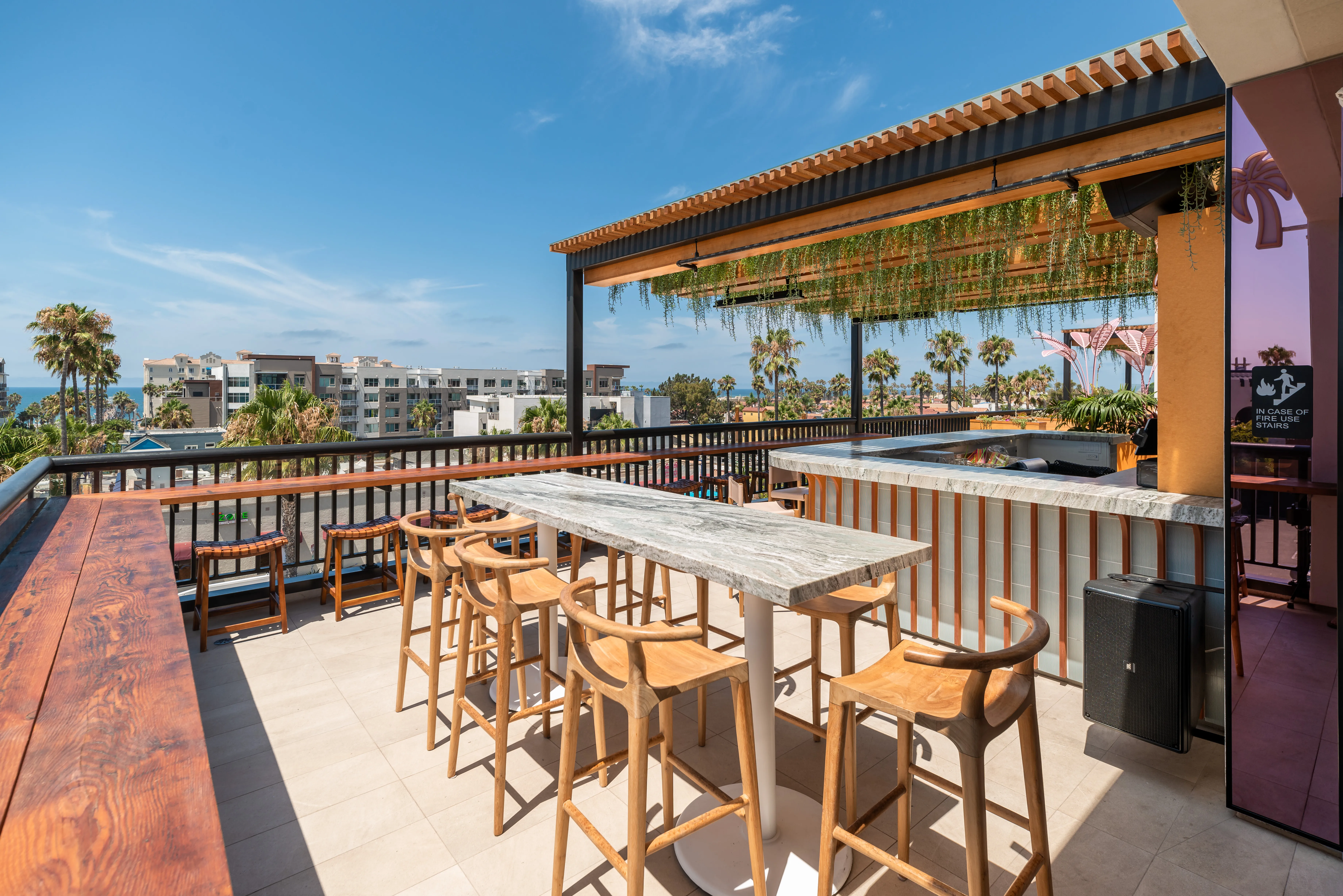 Coco Cabana lounge seating — pink daybeds, geometric tile wall, Oceanside skyline