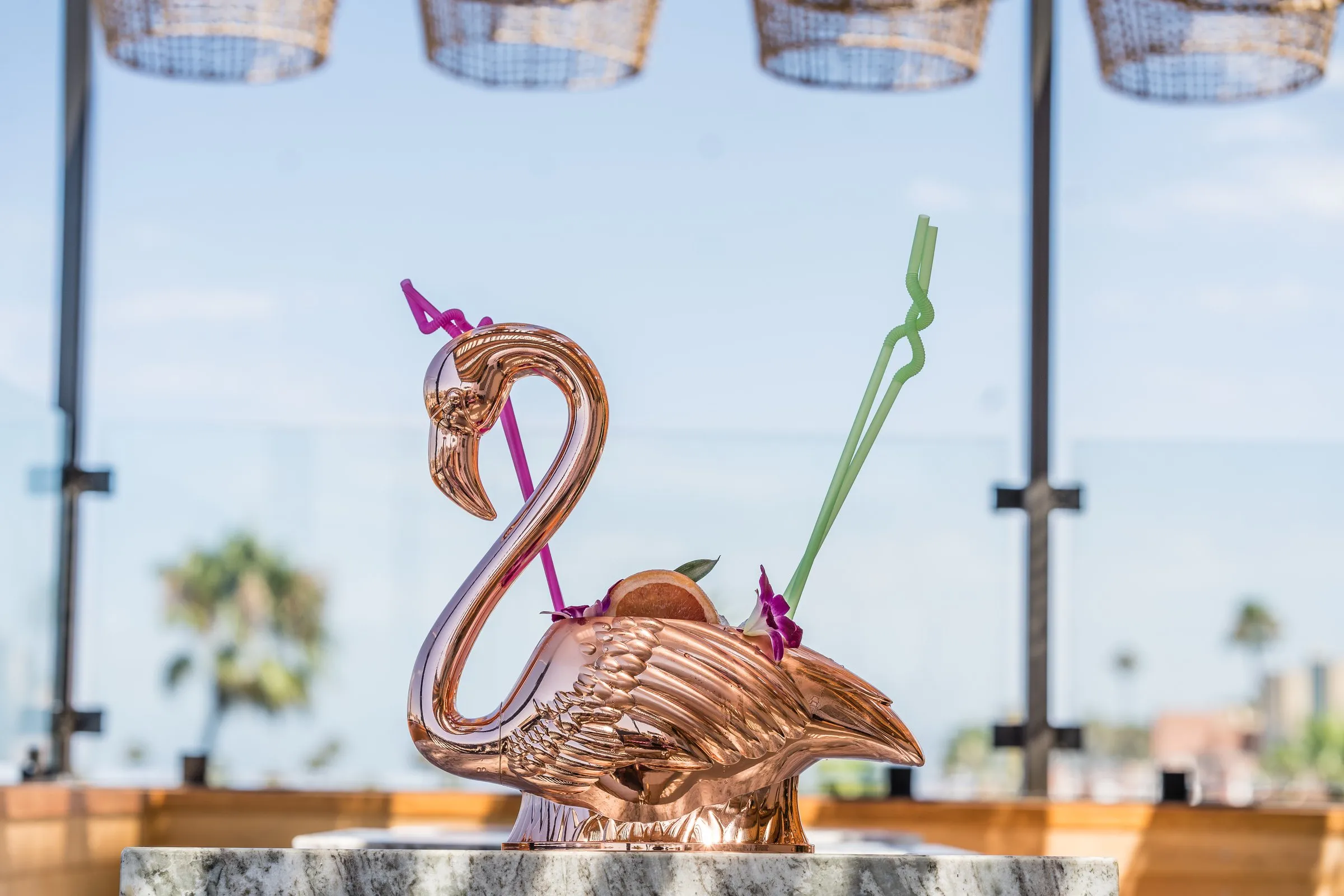 Coco Cabana signature copper flamingo cocktail vessel with rattan pendants and Oceanside rooftop